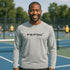 Man wearing a gray long-sleeve shirt with 'PEPIN' logo on a tennis court